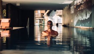 Mann im Panorama-Pool mit Seeblick im Adults Only Hotel Cortisen am Wolfgangsee