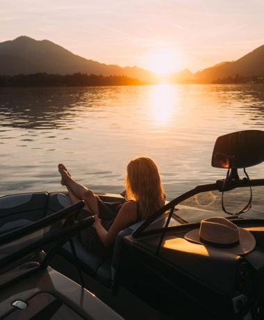 Frau genießt Sonnenuntergang auf dem Boot auf dem Wolfgangsee