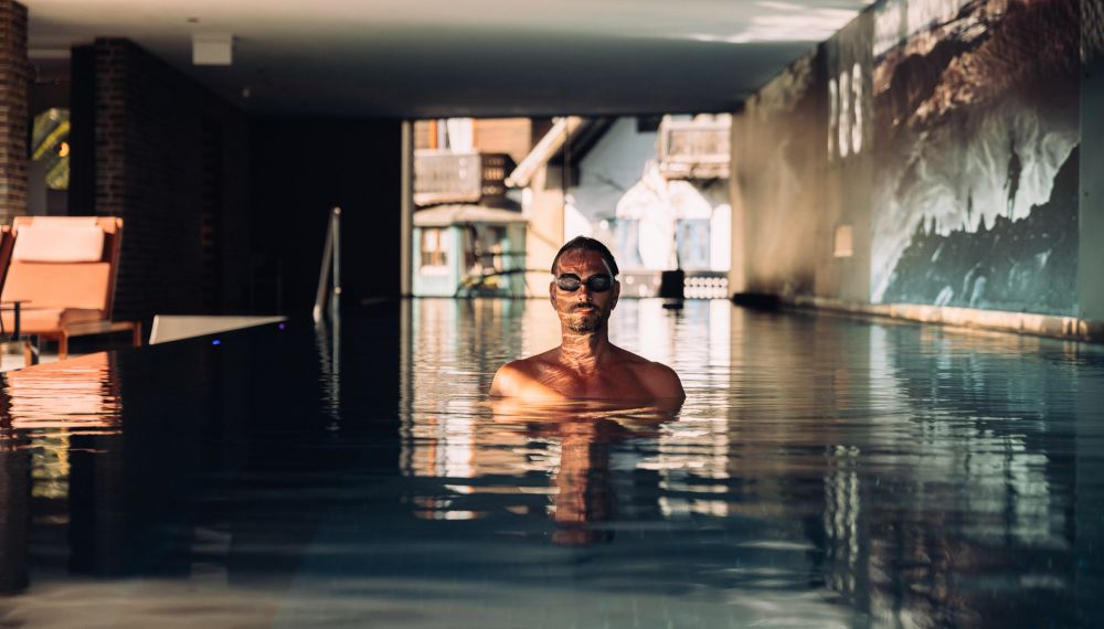 Mann im Panorama-Pool mit Seeblick im Adults Only Hotel Cortisen am Wolfgangsee