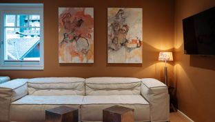 Kunstwerk über dem Sofa im Deluxe Zimmer Bergblick im Boutiquehotel Cortisen am Wolfgangsee mit stilvollem Interieur und moderner Atmosphäre
