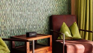 Detailaufnahme im Deluxe Zimmer Seeblick im Boutiquehotel Cortisen am Wolfgangsee mit stilvollem Sessel, Marshall Box und moderner Designtapete