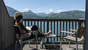 Frau sitzt auf dem Balkon des Premium Zimmers mit Seeblick im Adults Only Hotel Cortisen am Wolfgangsee