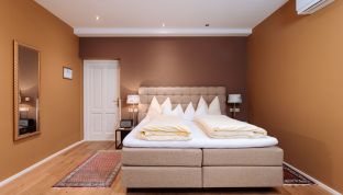 Elegantes Bett im Deluxe Zimmer Bergblick im Boutiquehotel Cortisen am Wolfgangsee mit hochwertigem Schlafkomfort und modernem Interieur