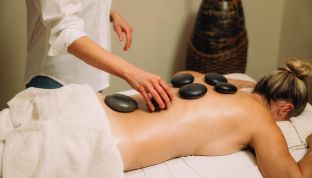 Frau auf einer Liege bekommt eine Hot Stone Massage im Adults Only Hotel Cortisen am Wolfgangsee