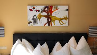 Bett im Deluxe Zimmer Seeblick im Boutiquehotel Cortisen am Wolfgangsee mit modernem Kunstwerk an der Wand und stilvollem Interieur