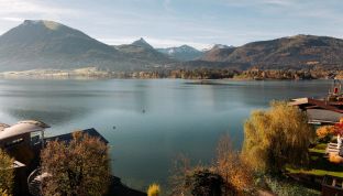 Herbstlicher Ausblick aus der Loft Suite im Boutiquehotel Cortisen am Wolfgangsee mit warmen Farben, ruhigem Wasser und Blick auf die Berge