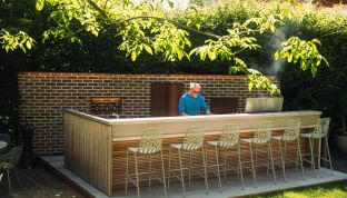 Mann grillt in der Outdoor Kitchen im Boutqiue Hotel Cortisen am Wolfgangsee