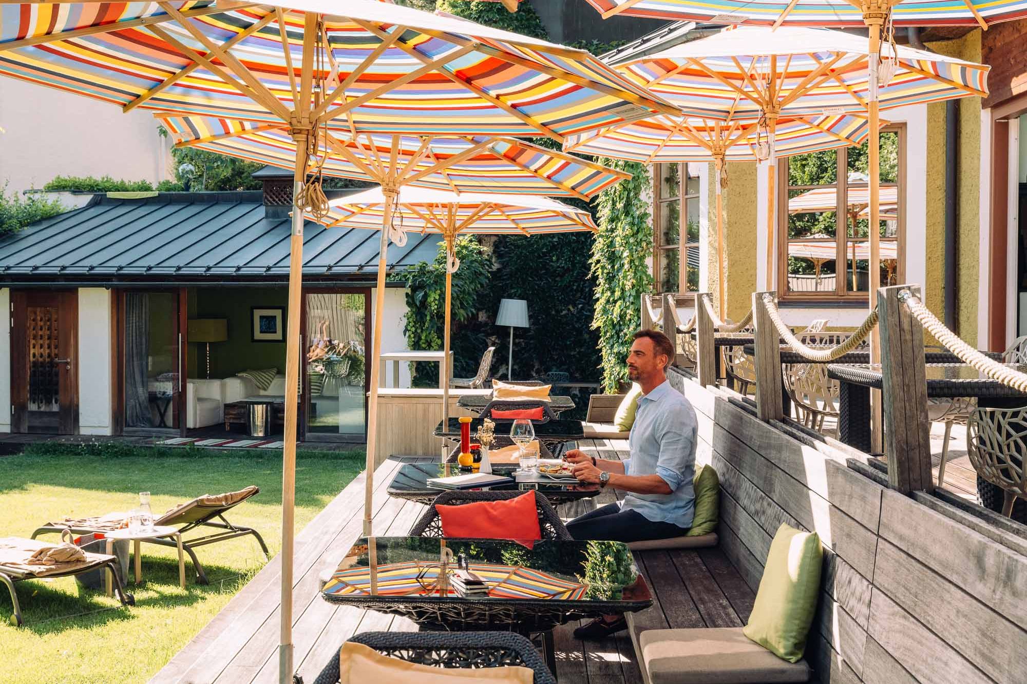 Mann sitzt auf der Terrasse mit Seeblick im Sommer im Adults Only Boutique Hotel Cortisen am Wolfgangsee