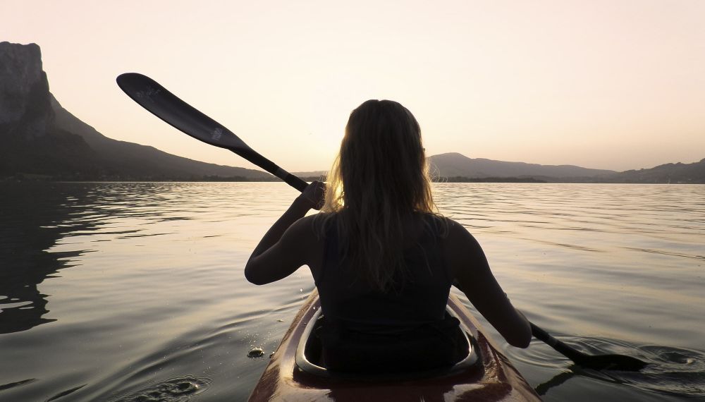 Frau fährt beim Sonnenuntergang Kanu auf dem Wolfgangsee