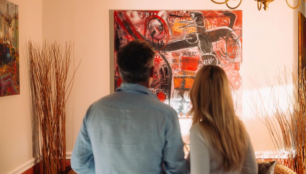 Paar betrachtet Kunstgemälde im Adults Only Design Hotel Cortisen am Wolfgangsee im Salzkammergut