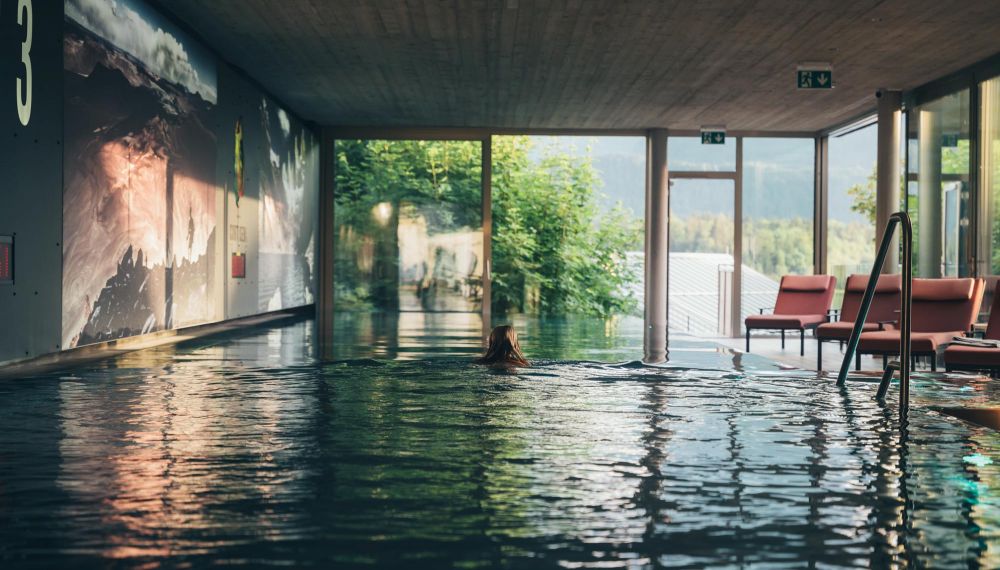 Frau schwimmt im Infinity-Pool im Boutique Hotel Cortisen am Wolfgangsee im Salzkammergut