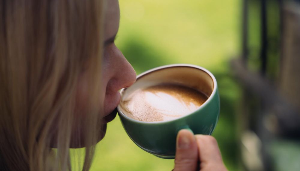 Frau trinkt Kaffee im Garten des Adults Only Boutique Hotel Cortisen am Wolfgangsee im Salzkammergut