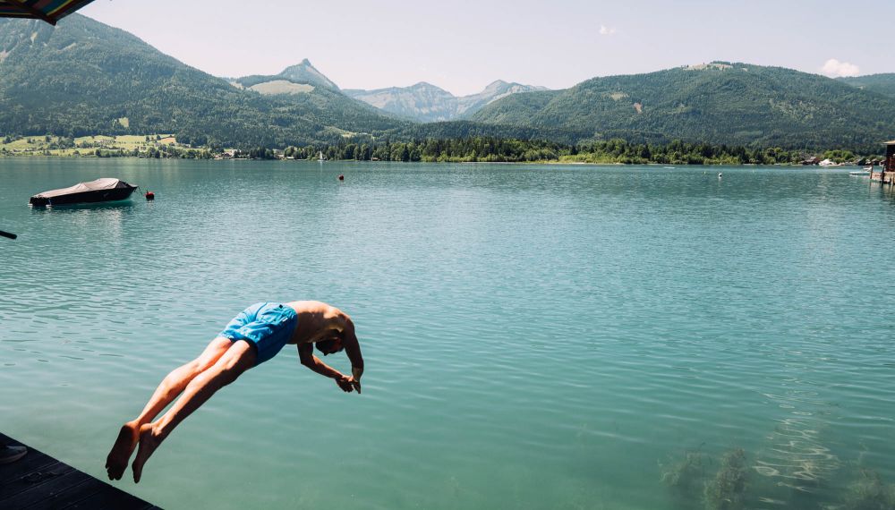 Mann springt in den Wolfgangsee vom Boutique Hotel Cortisen im Salzkammergut aus