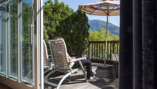 Frau auf der Terrasse der Design Suite im Cortisen am See mit Blick auf den Wolfgangsee