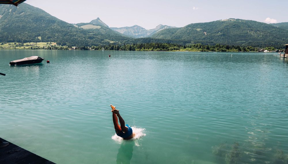 Mann springt vom Steg des Adults Only Boutique Hotels mit eigenem Seezugang in den Wolfgangsee