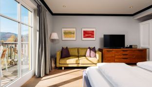 Deluxe Zimmer Seeblick im Boutiquehotel Cortisen am Wolfgangsee mit modernem Interieur, warmen Farben und direktem Blick auf den Balkon