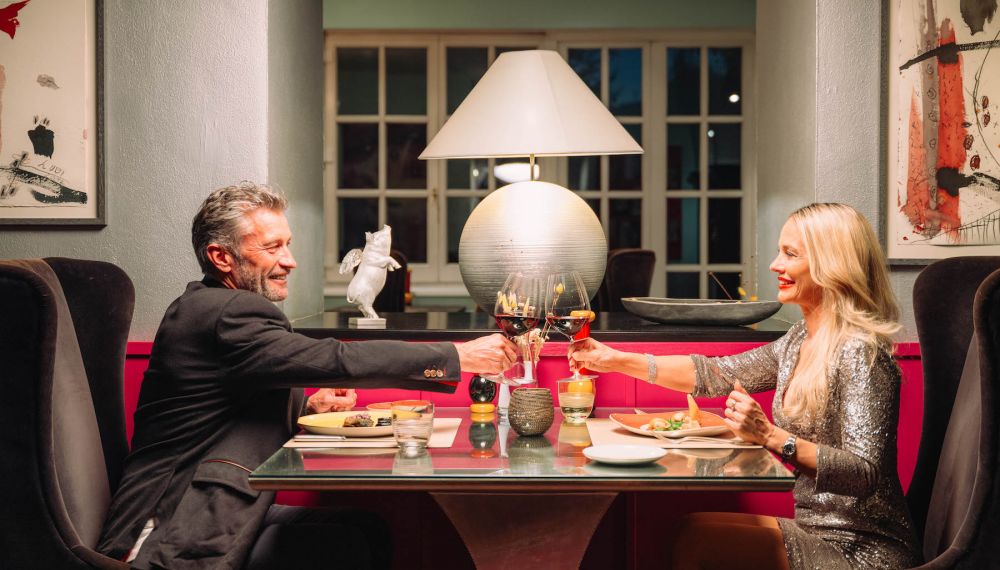Paar stößt bei einem romantischen Dinner im Adults Only Boutique Hotel am Wolfgangsee mit Wein an