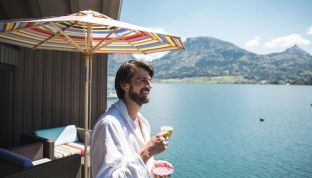 Mann trinkt Kaffee auf dem Balkon des Bootshauses im Adults Only Hotel Cortisen direkt am Wolfgangsee