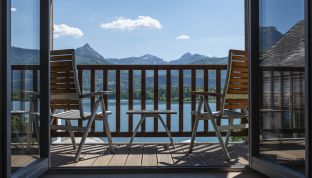 Balkon des Doppelzimmers Deluxe mit zwei Stühlen und Seeblick im Boutiquehotel Cortisen am Wolfgangsee