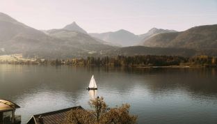 Blick vom Boutique Hotel Cortisen am See auf ein Segelboot auf dem Wolfgangsee im Nebel