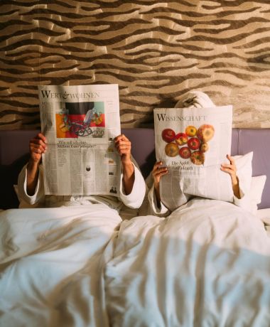 Paar liest Zeitung im Bett eines Design Zimmers im Boutique Hotel am Wolfgangsee