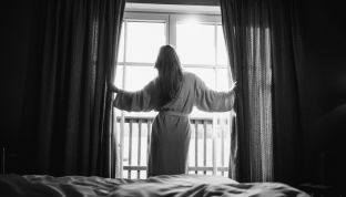 Frau steht am Fenster im Zimmer des 4-Sterne Boutique Hotels Cortisen am Wolfgangsee