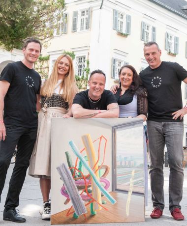 Menschen mit Gemälde posieren beim Art Circle am Wolfgangsee im Designhotel im Salzkammergut
