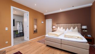 Deluxe Zimmer Bergblick im Boutiquehotel Cortisen am Wolfgangsee mit Blick auf das moderne Badezimmer, hochwertigem Interieur und gemütlichem Wohnbereich