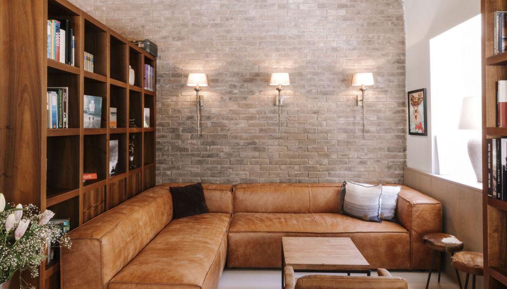 Ledercouch und Bücherregale in der Sitzecke im Designhotel Cortisen am Wolfgangsee