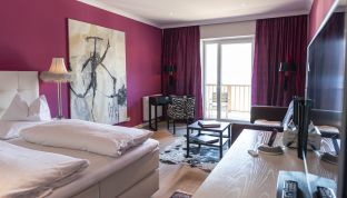 Schlafzimmer mit Doppelbett und Sitzecke in der White Suite im Designhotel am Wolfgangsee