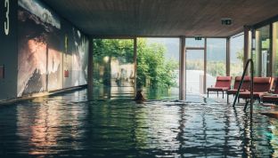 Frau schwimmt im Infinity-Pool im Boutique Hotel Cortisen am Wolfgangsee im Salzkammergut