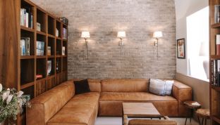 Ledercouch und Bücherregale in der Sitzecke im Designhotel Cortisen am Wolfgangsee