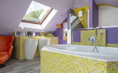Bad der Owner Suite mit gelbem Mosaik und lila Wänden im Designhotel Cortisen am Wolfgangsee