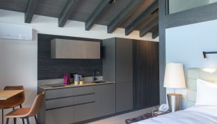 Küchenzeile neben dem Bett in der Boatshed Suite im Designhotel Cortisen am Wolfgangsee