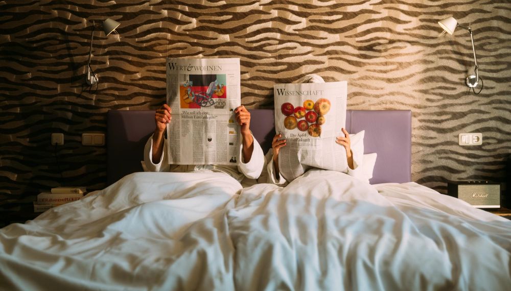 Paar liest Zeitung im Schlafzimmer im Designhotel Cortisen am Wolfgangsee