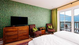 Deluxe Zimmer Seeblick im Boutiquehotel Cortisen am Wolfgangsee mit stilvoller Tapete, modernem TV und direktem Zugang zum Balkon mit Blick auf den See