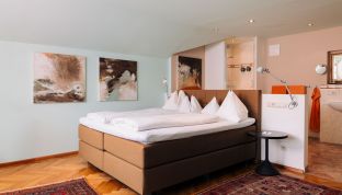 Bett und Kunstwerk in der Loft Suite im Boutiquehotel Cortisen am Wolfgangsee mit stilvollem Interieur und hochwertigem Design