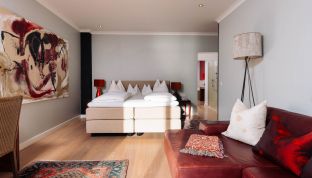 Zimmer der Red Suite Design Suite im Boutiquehotel Cortisen am Wolfgangsee mit stilvollen Designelementen, warmen Farbtönen und modernem Interieur