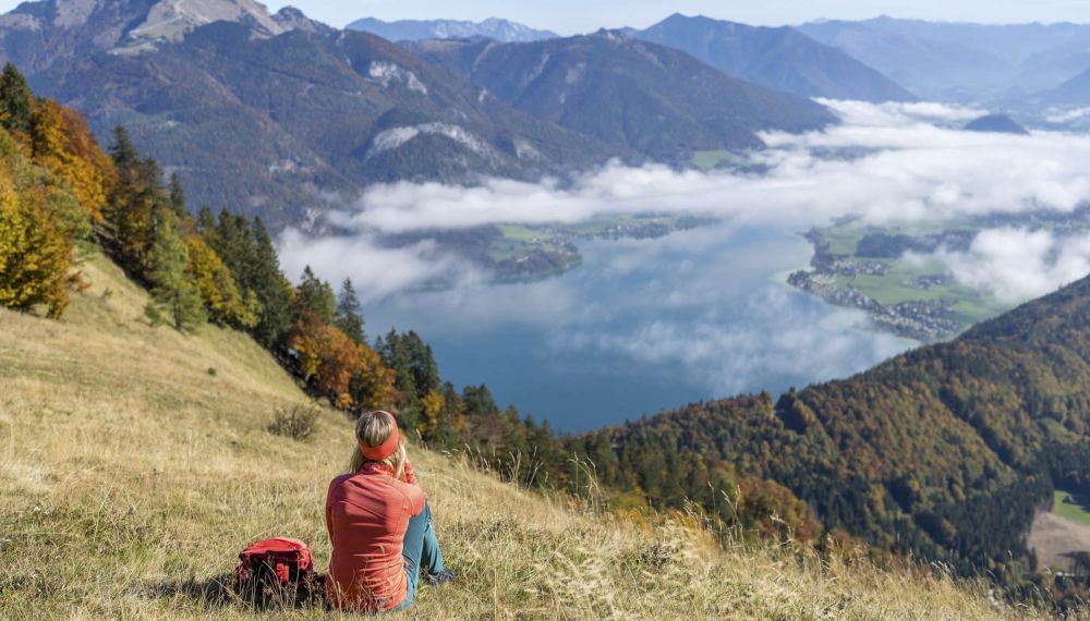 Frau macht eine Pause mit Blick auf den Wolfgangsee bei ihrer Wanderung