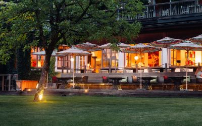 hell erleuchtete Terrasse des Boutique Hotels Cortisem am Wolfgangsee bei Sonnenuntergang mit Garten und direktem Seezugang